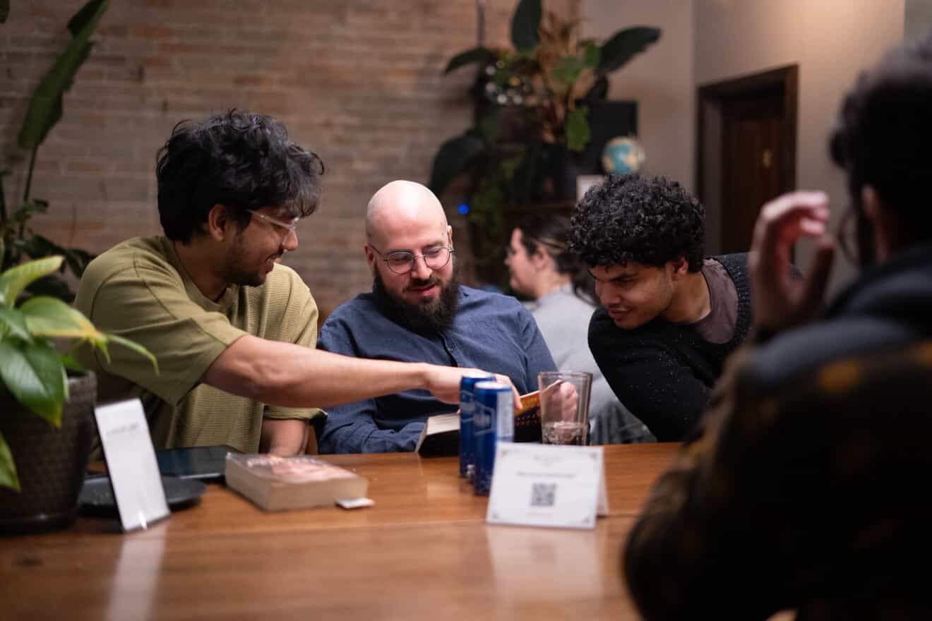 Three attendees smiling together and sharing something from a book