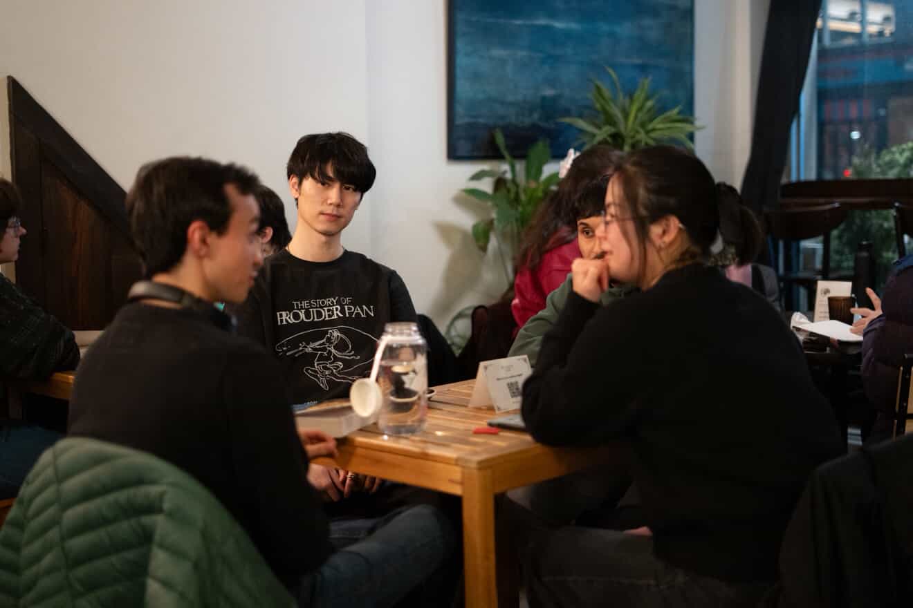 A small group of Margins Club attendees talking together around a café table